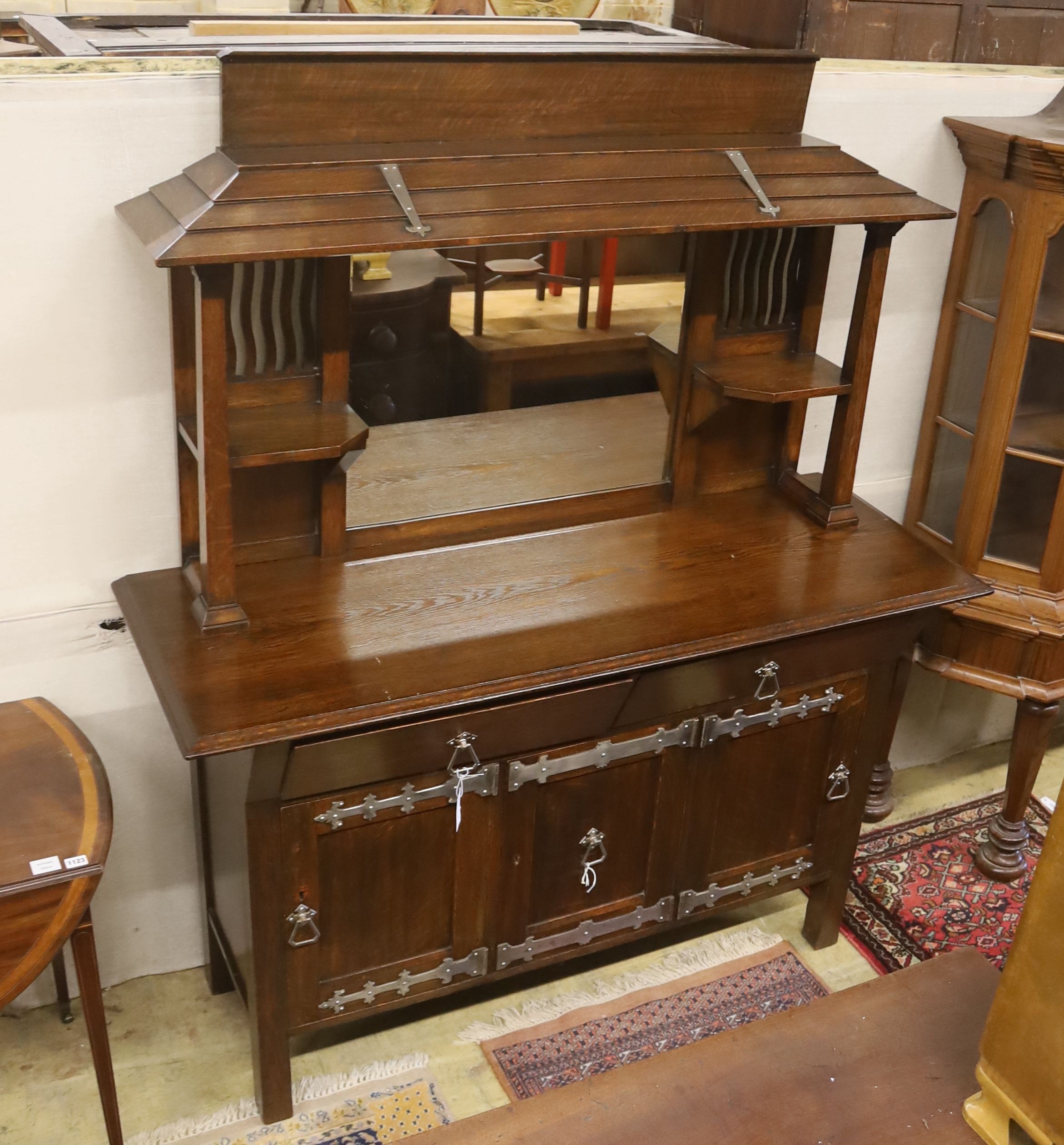 An early 20th century Arts & Crafts oak and polished steel mirrored sideboard, in the manner of Liberty & Co., length 152cm, depth 56cm, height 184cm